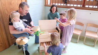 Kinder probieren die Instrumente des Instrumentewagens aus.